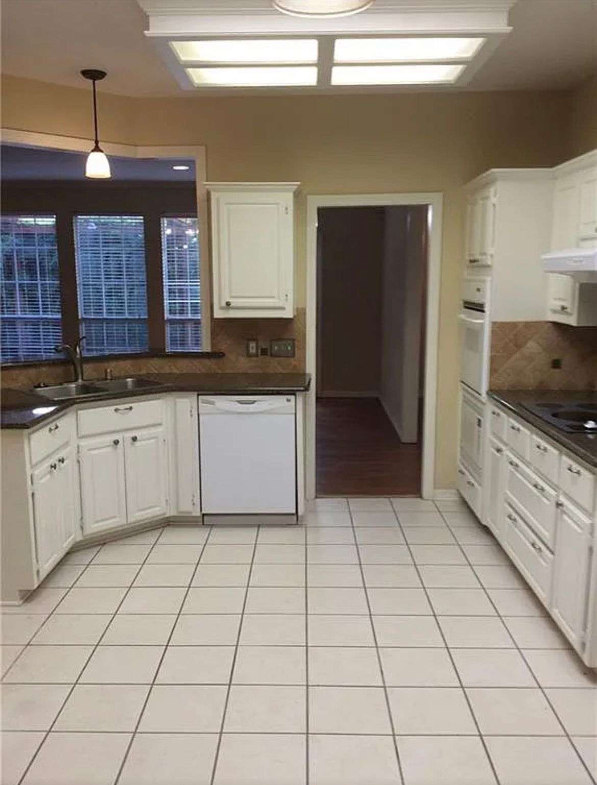 An empty kitchen with white cabinets and a white dishwasher