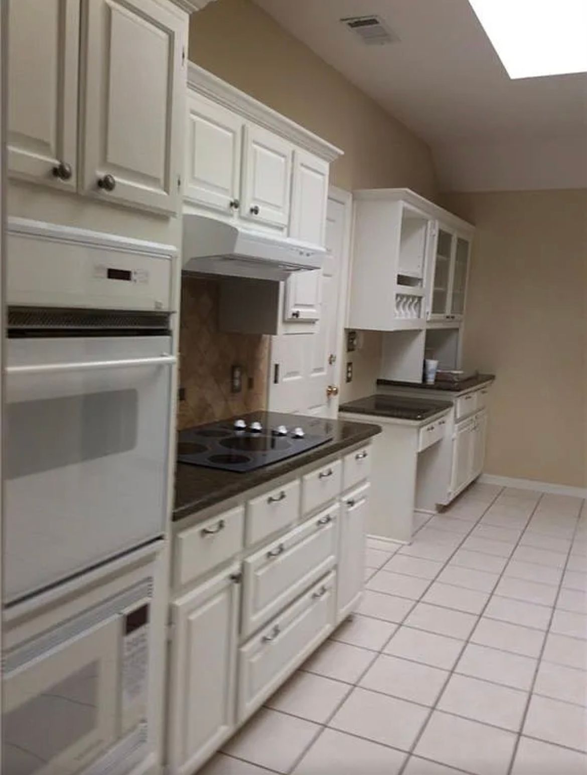 A kitchen with white cabinets and black counter tops