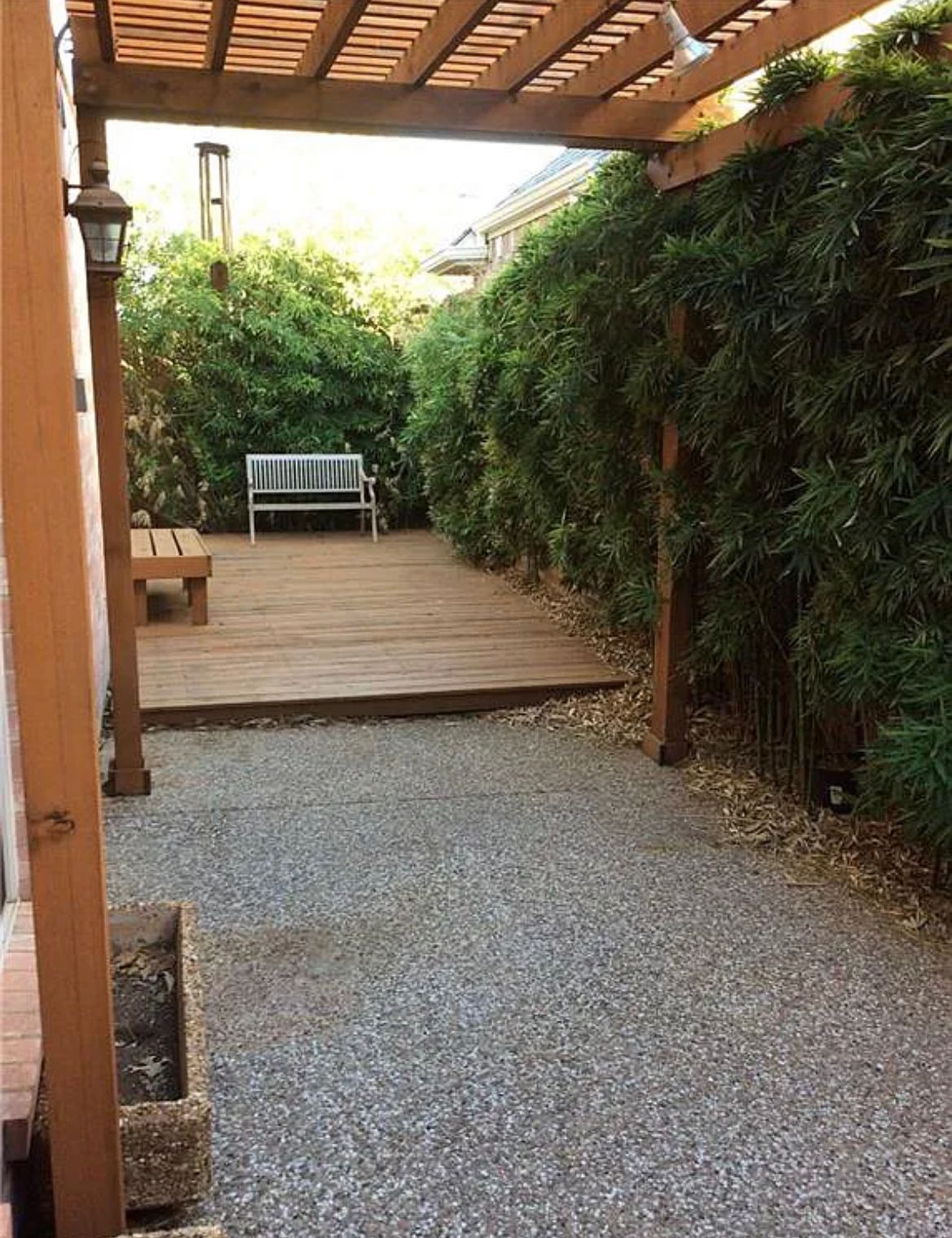 A wooden deck with a bench under a pergola