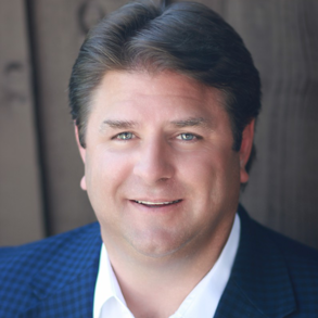 A man in a suit and white shirt is smiling for the camera