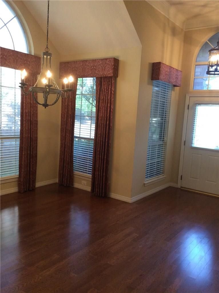 An empty room with a chandelier hanging from the ceiling
