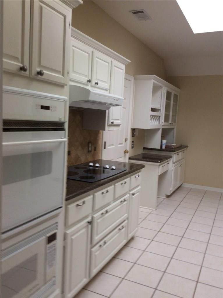 A kitchen with white cabinets and black counter tops