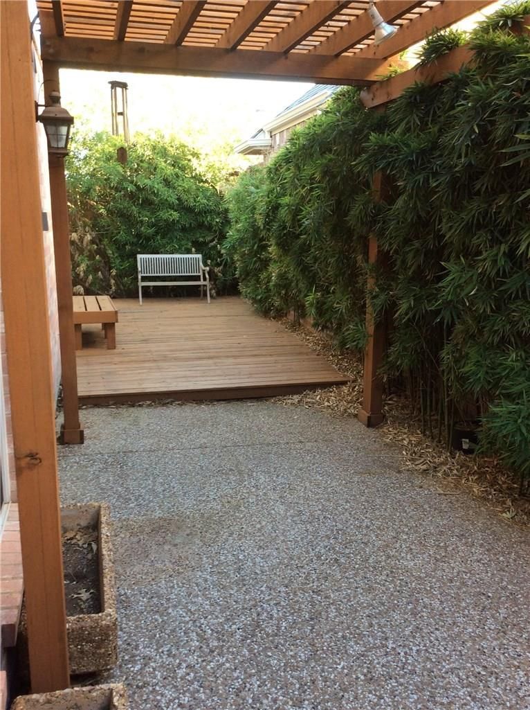 A wooden deck with a bench under a pergola
