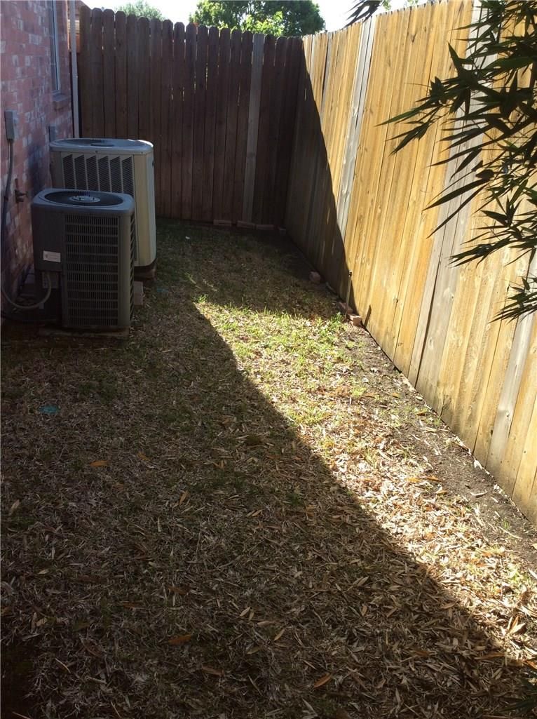 A backyard with a wooden fence and an air conditioner