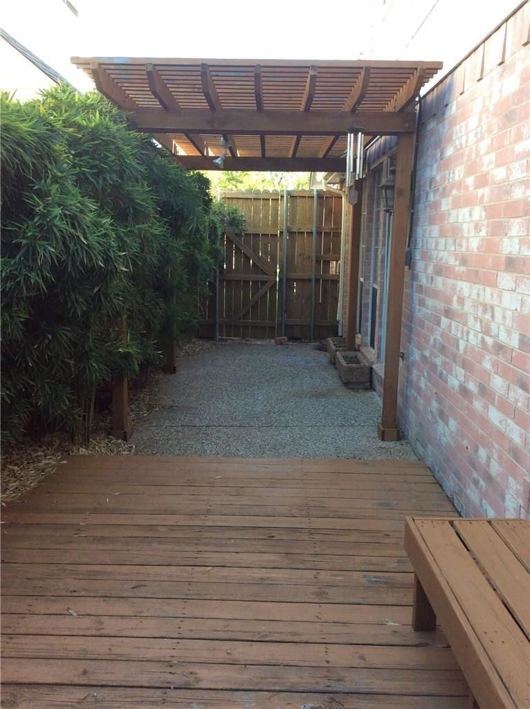 A wooden deck with a bench underneath a pergola
