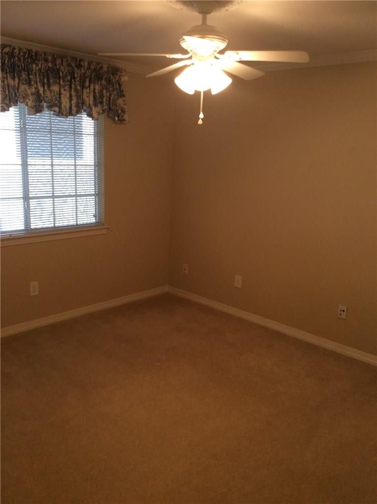 An empty room with a ceiling fan and a window.