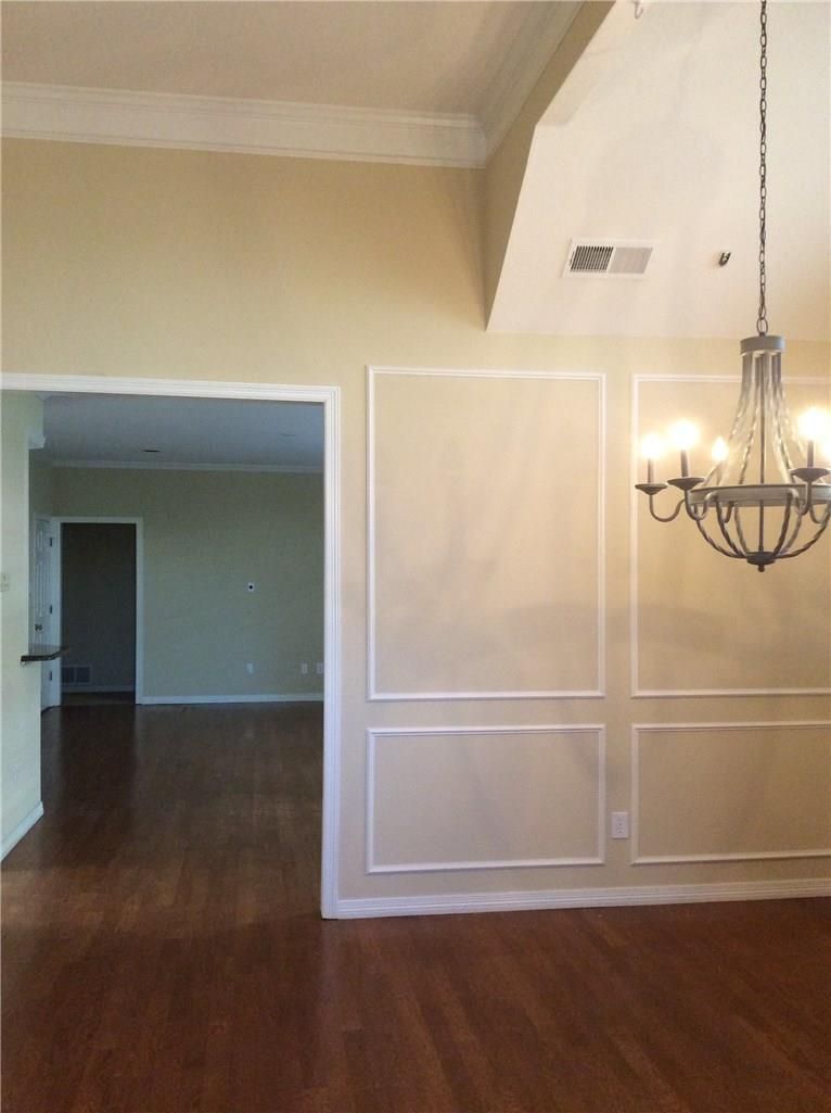 An empty dining room with a chandelier hanging from the ceiling