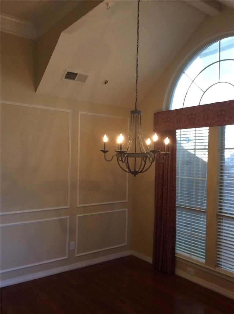 An empty room with a chandelier hanging from the ceiling
