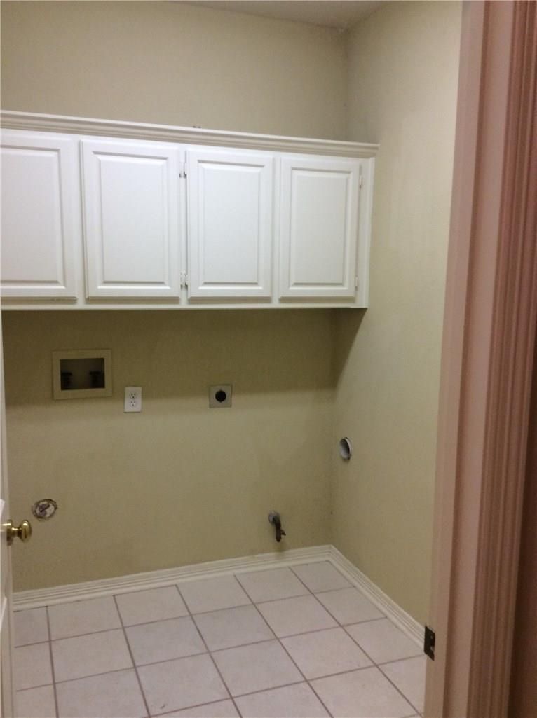 A laundry room with white cabinets and tile floors