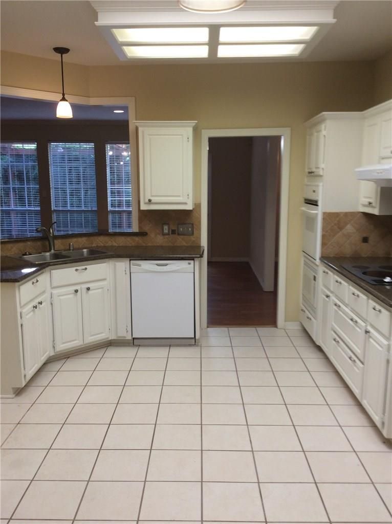 An empty kitchen with white cabinets and black counter tops