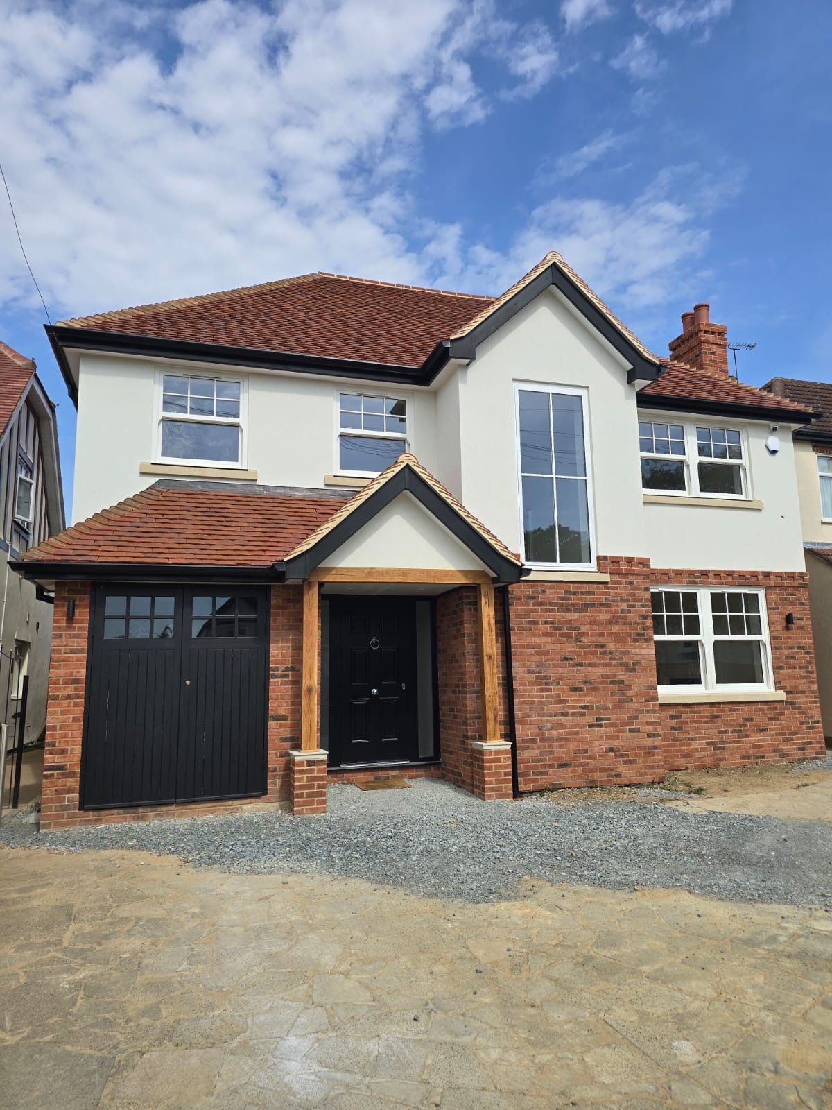 Two-story house with red brick and white stucco exterior, red tile roof, and black garage door.