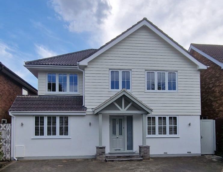 Two-story house with white siding and gray roof, a covered entry, and multiple windows.