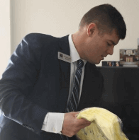 A man in a suit and tie is holding a yellow cloth