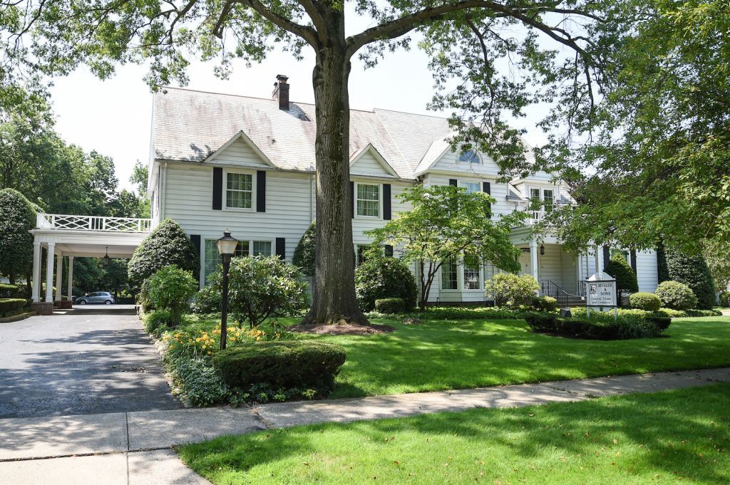 A large white house with a large tree in front of it