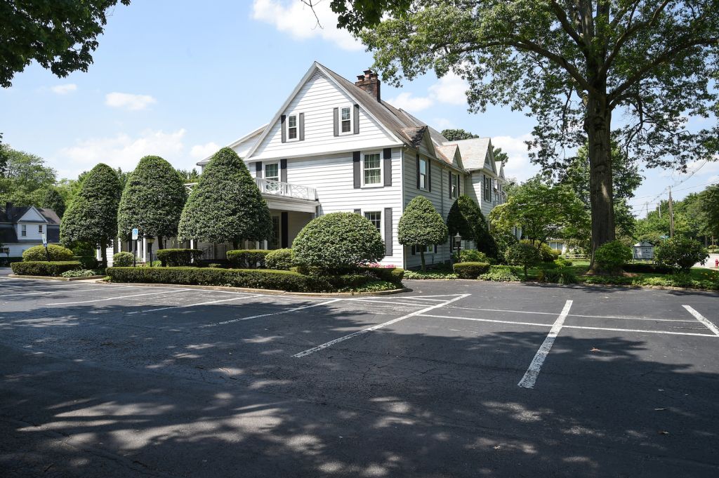 A large white house with a parking lot in front of it