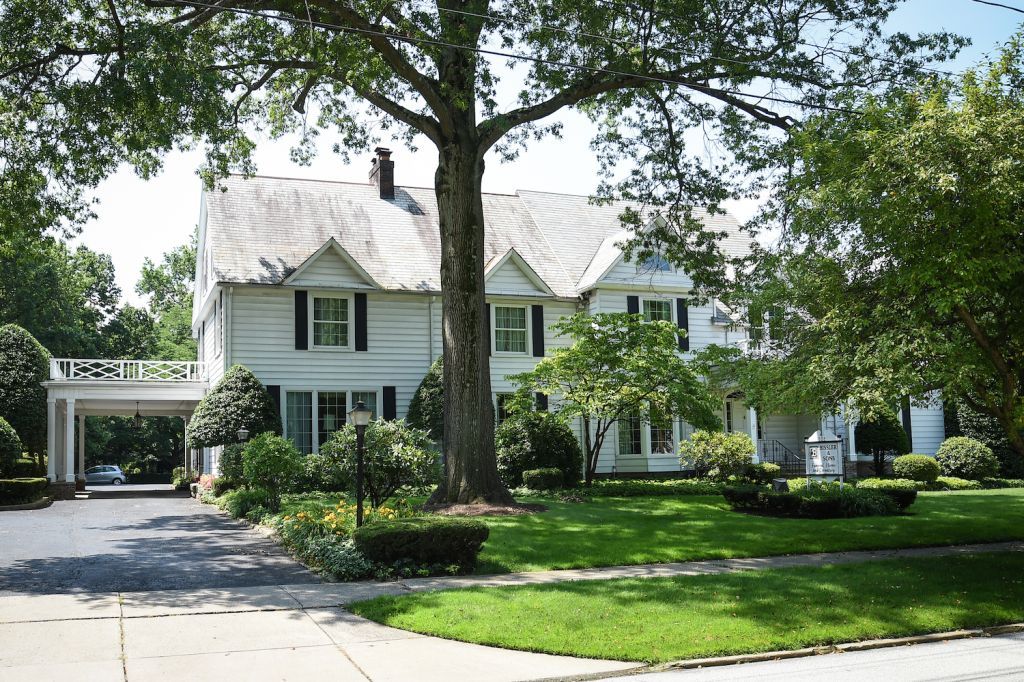 A large white house with a large tree in front of it
