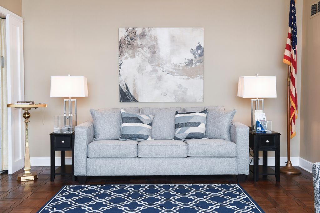 A living room with a couch , lamps , a rug and an american flag.
