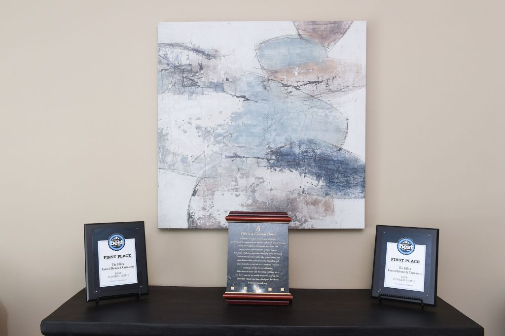 A table with a painting on the wall and two plaques on it.