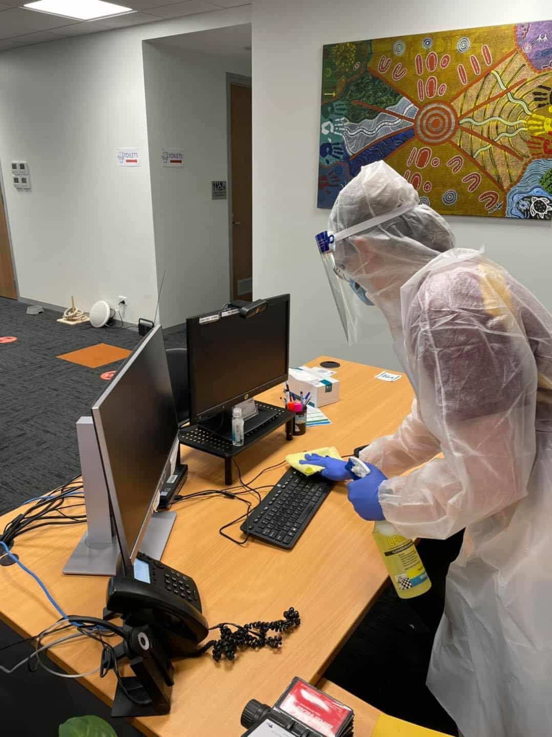 Cleaner Cleaning a Computer on an Office Desk — Carpet Cleaners in Tatura, VIC