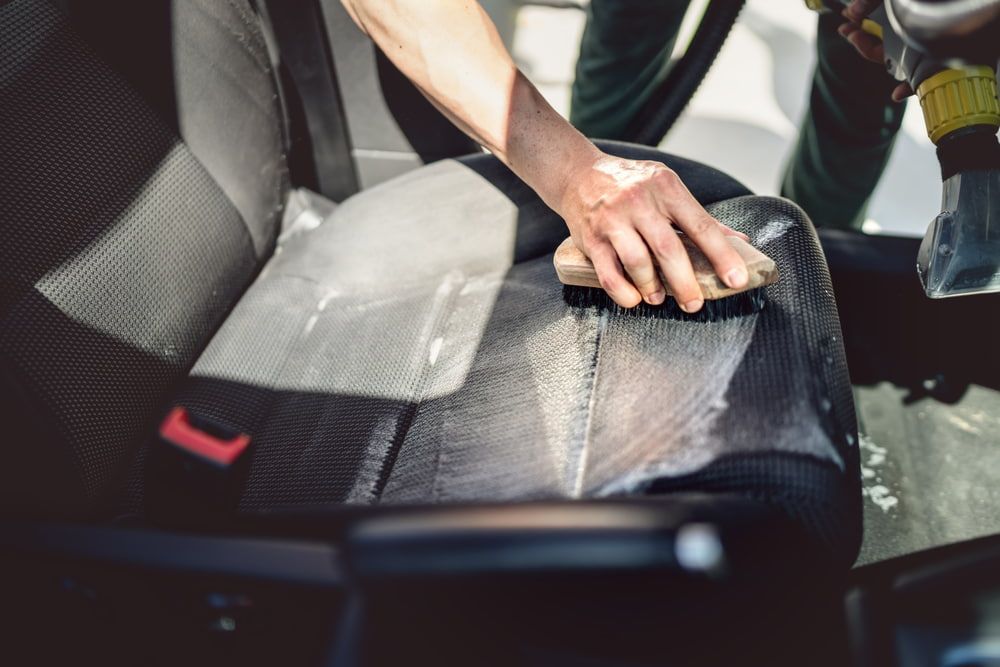 Someone Washing a Car Seat with a Brush — Carpet Cleaners in Tatura, VIC
