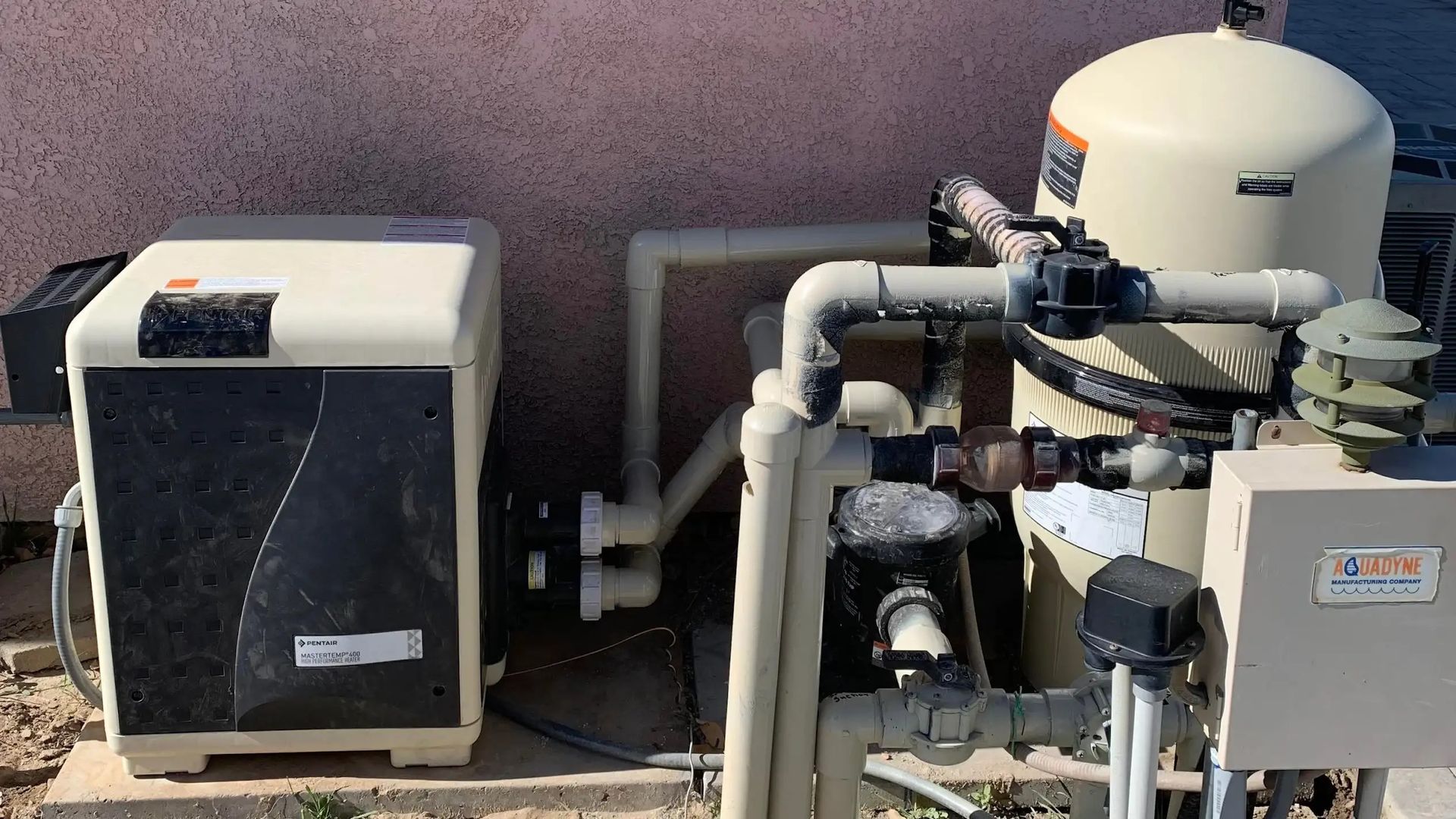 Outdoor HVAC equipment with pipes and compressor units on a concrete pad.