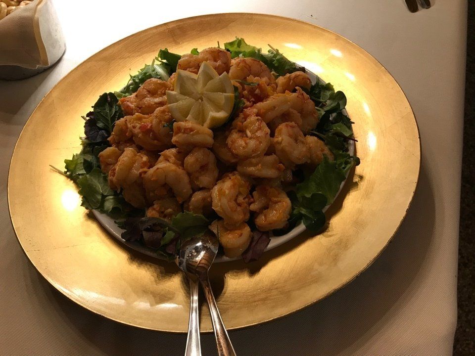 Un piatto d'oro con sopra gamberi e lattuga su un tavolo