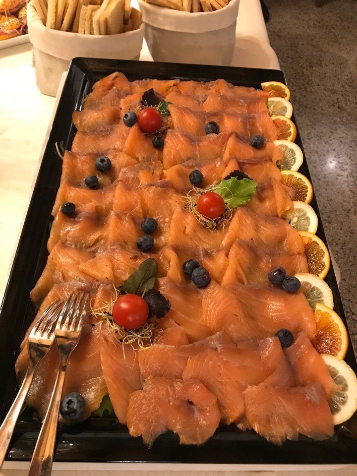 Un vassoio di salmone affumicato con mirtilli, pomodori, limoni e cracker su un tavolo.