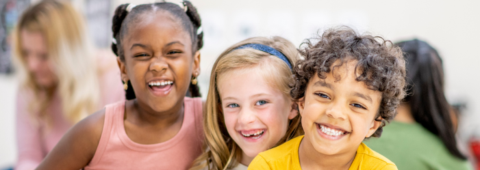 Effective Montessori Time Management for Kids | Three smiling elementary kids in a classroom setting
