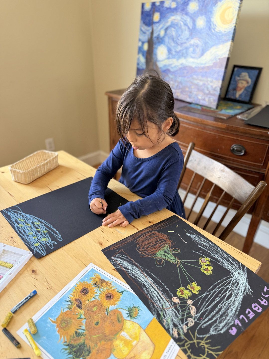 A primary Montessori child uses oil pastels on black paper to recreate Van Gogh's famous sunflower art.