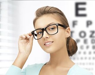 Young woman face in eyeglasses with eye chart - eye care in Medford, OR