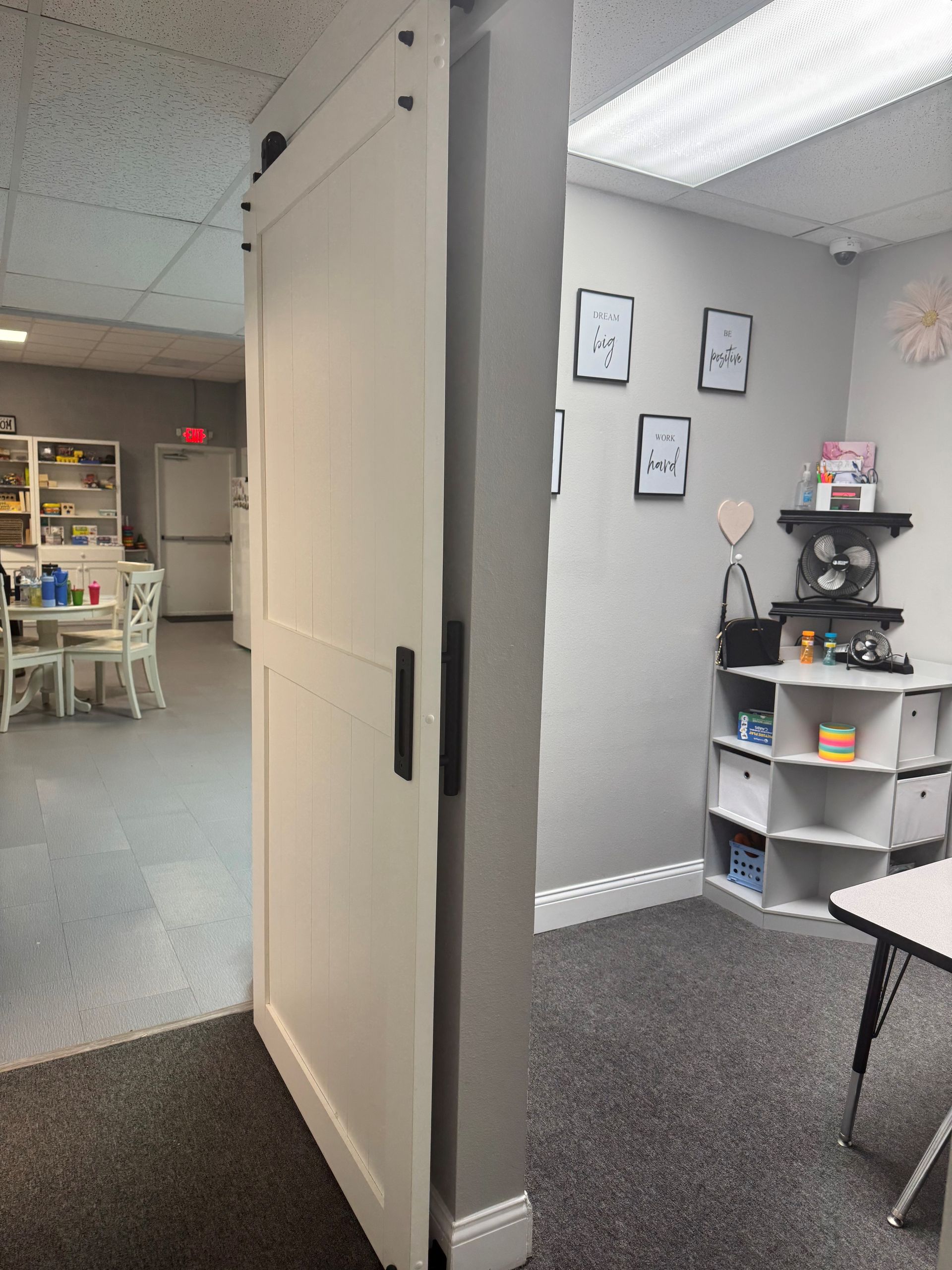 White barn door partially open, revealing a room with art supplies and a table.