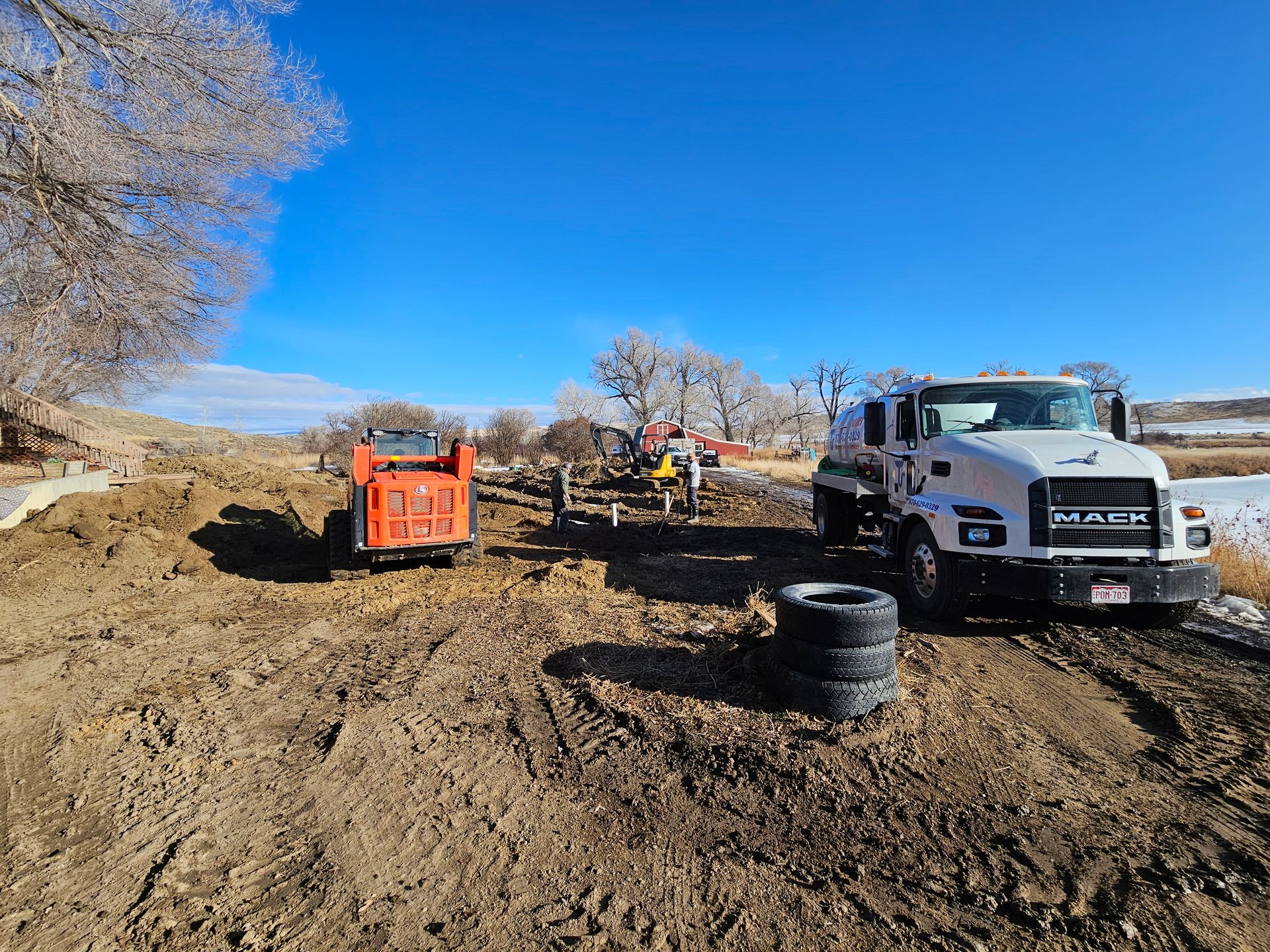 A man is walking next to a bobcat excavator on a dirt road.