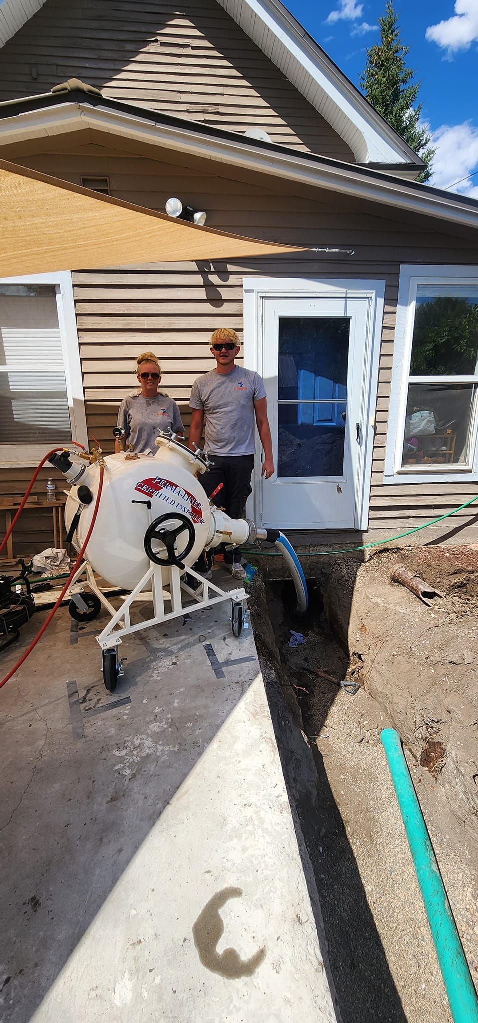 Two men are standing in front of a house with a machine in front of them.