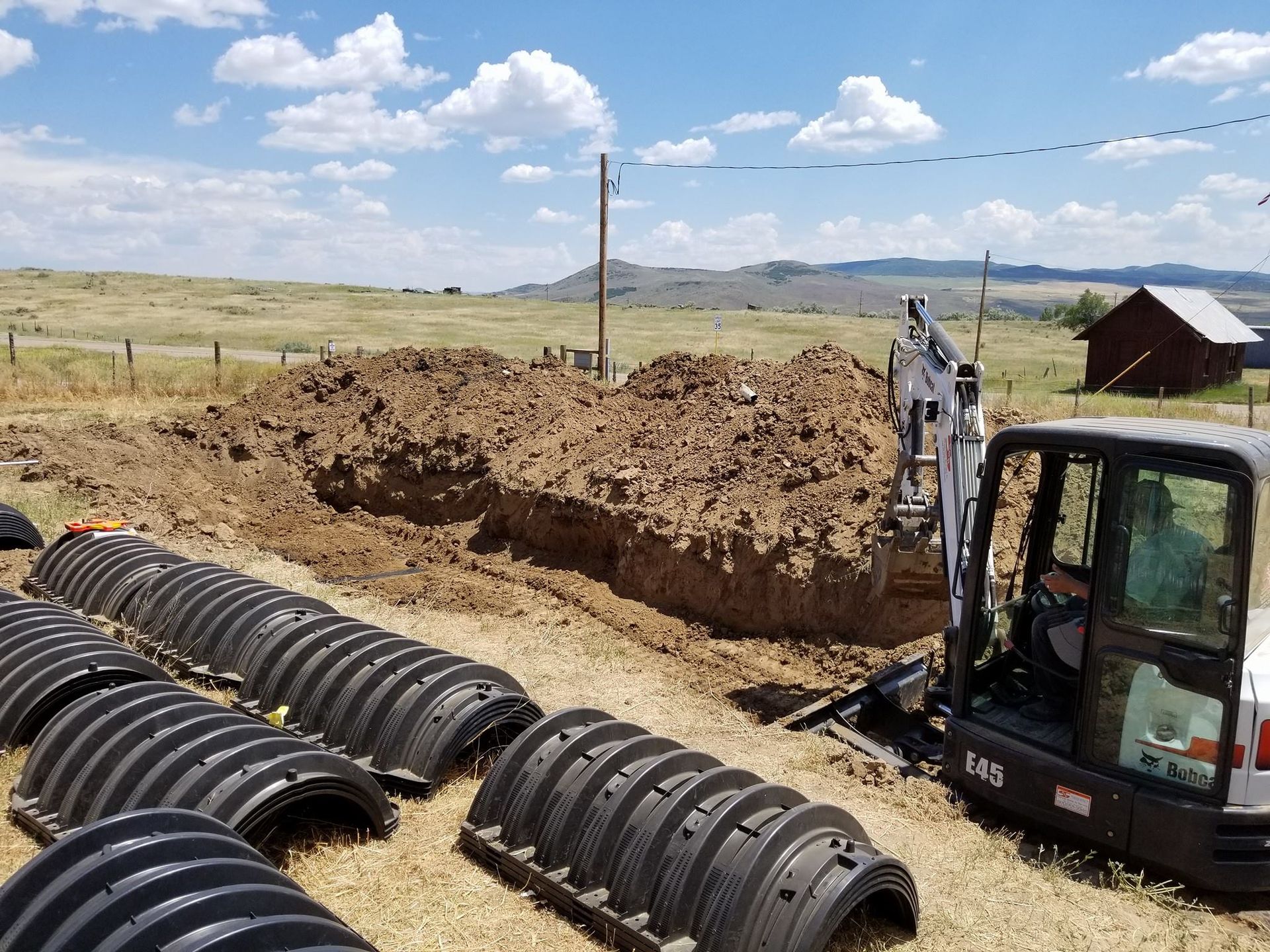 A man is driving a small excavator in a field.