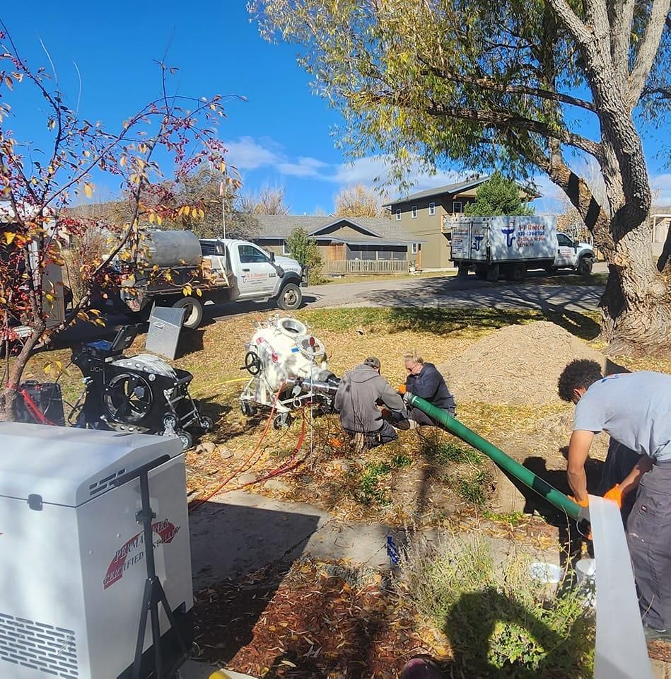 A group of men are working on a green pipe in a yard.