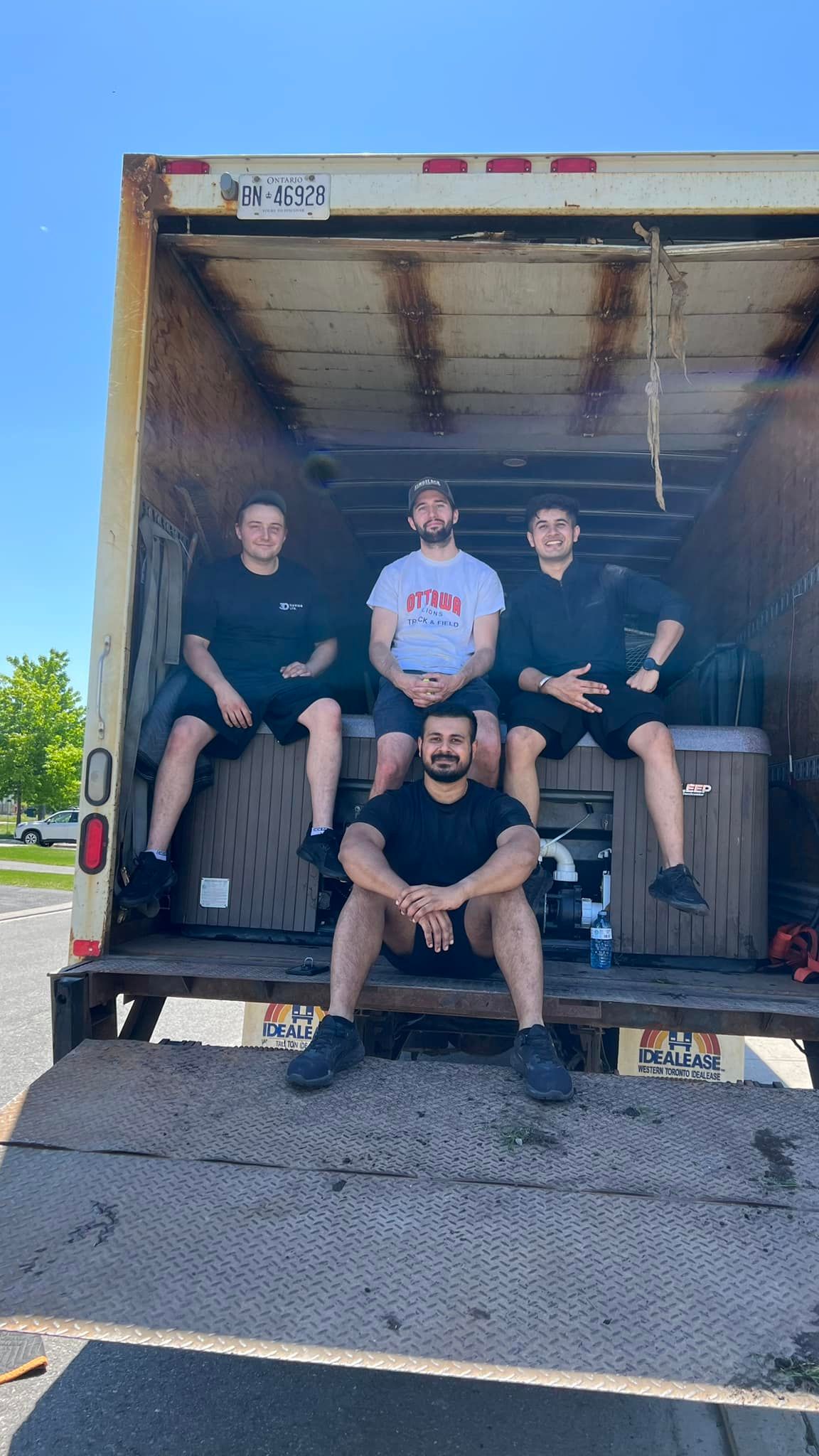 four men are sitting in the back of an idealease truck