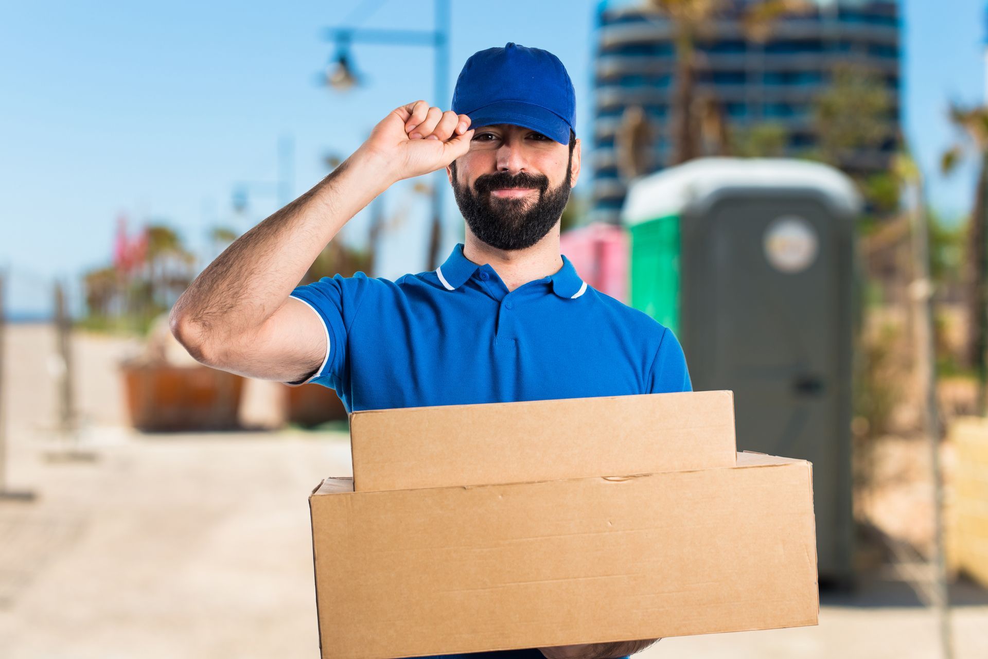 a delivery man in a blue shirt is holding a cardboard box