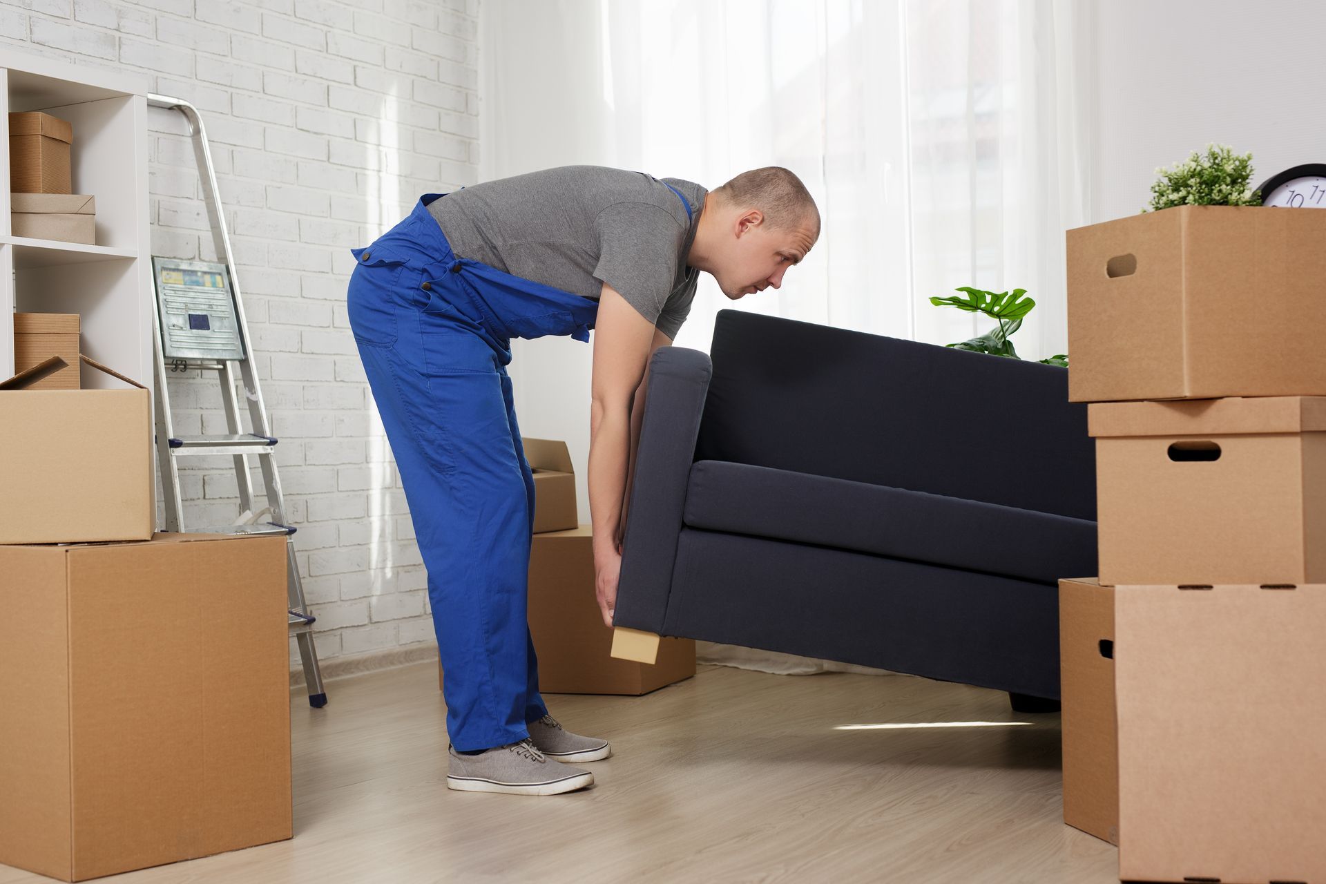 a man in blue overalls is lifting a couch