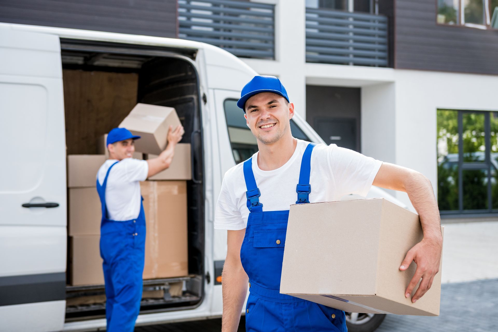a man in blue overalls is holding a cardboard box