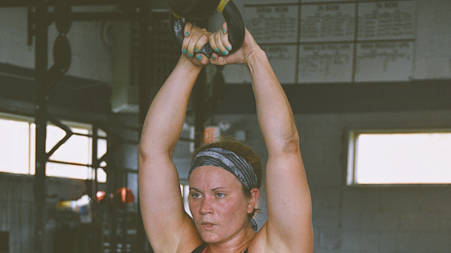 a woman is lifting a kettlebell over her head in a gym
