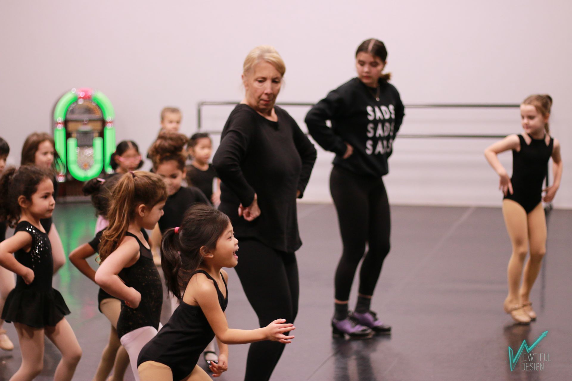 A group of young girls are dancing in a dance studio.