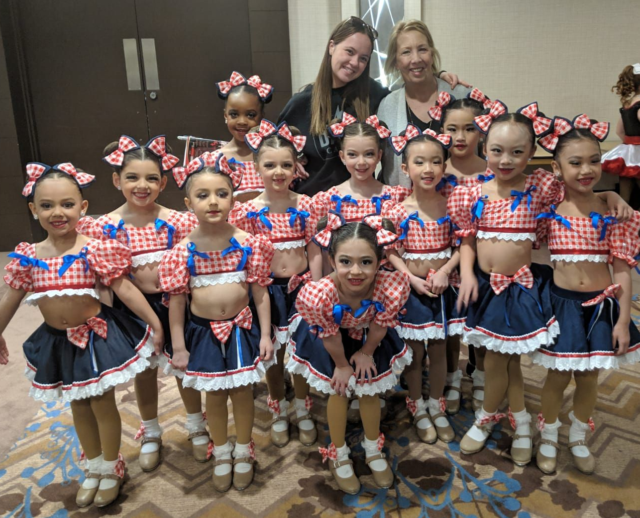 Three little girls are doing splits in a gym.