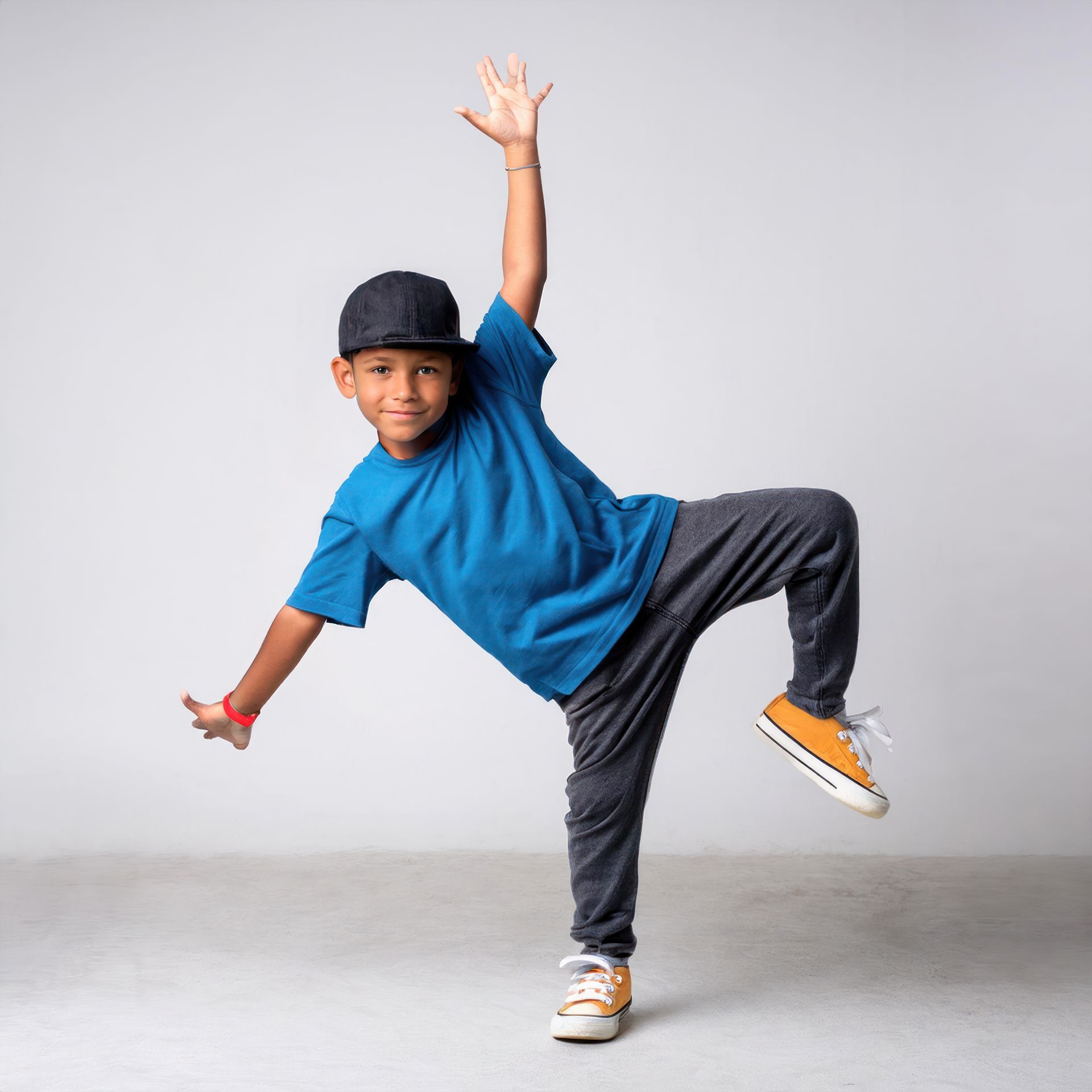 A young boy in a blue shirt and hat is dancing.