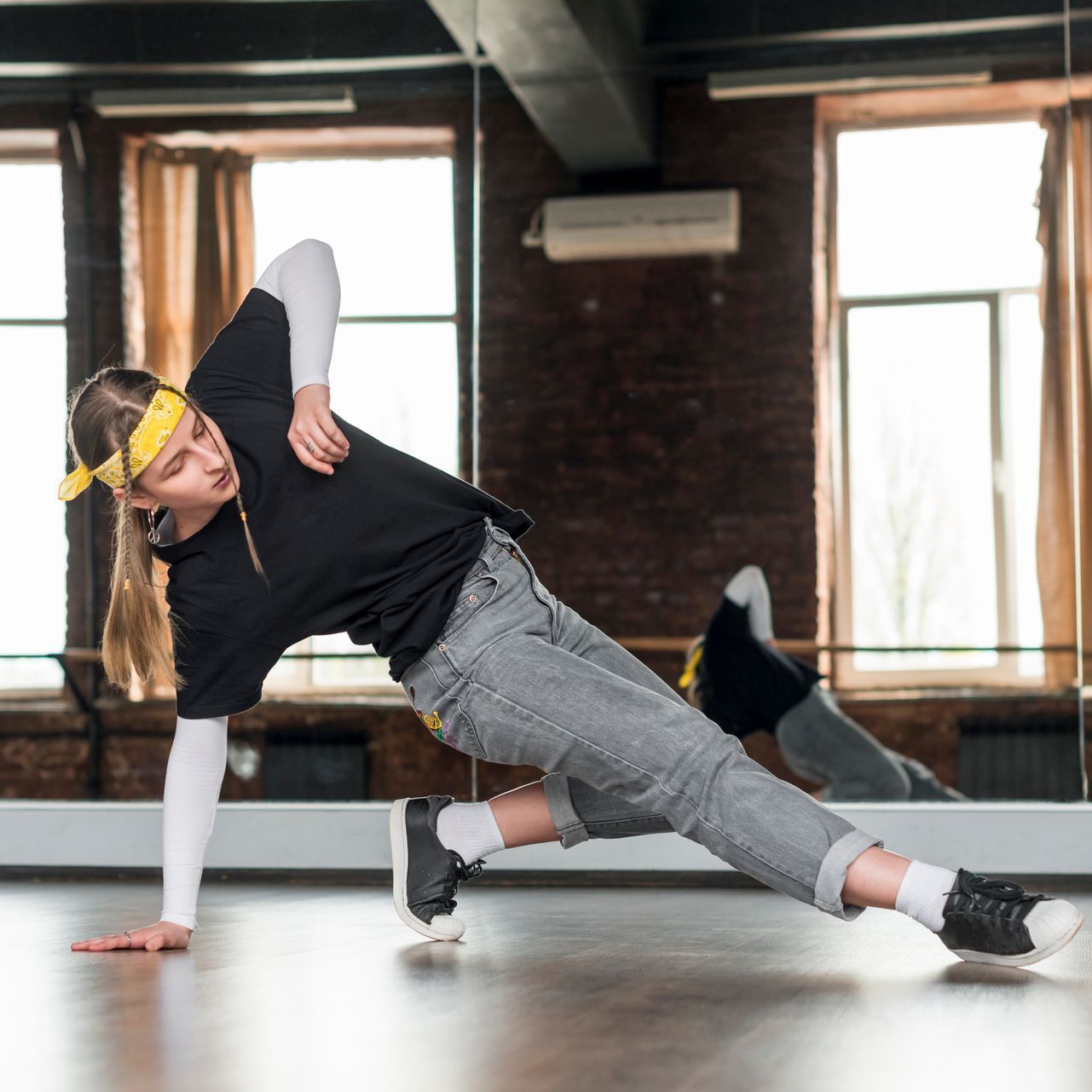 A woman is doing a handstand in front of a mirror in a dance studio.