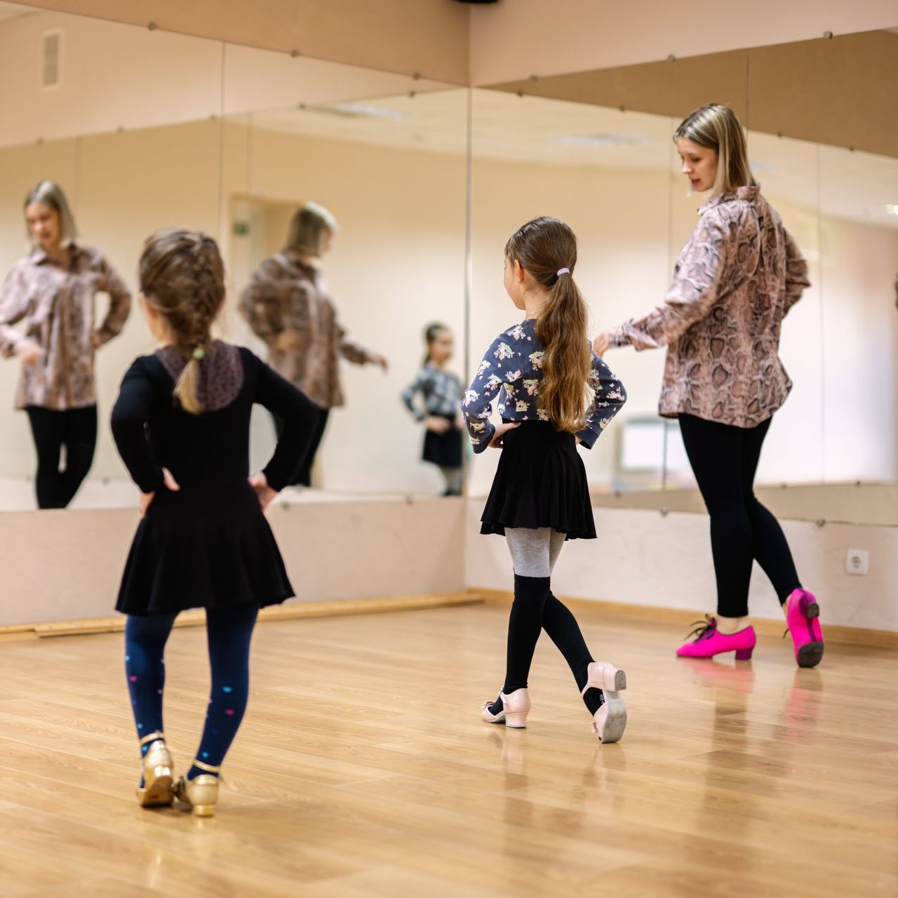 Two little girls are dancing in front of a large mirror