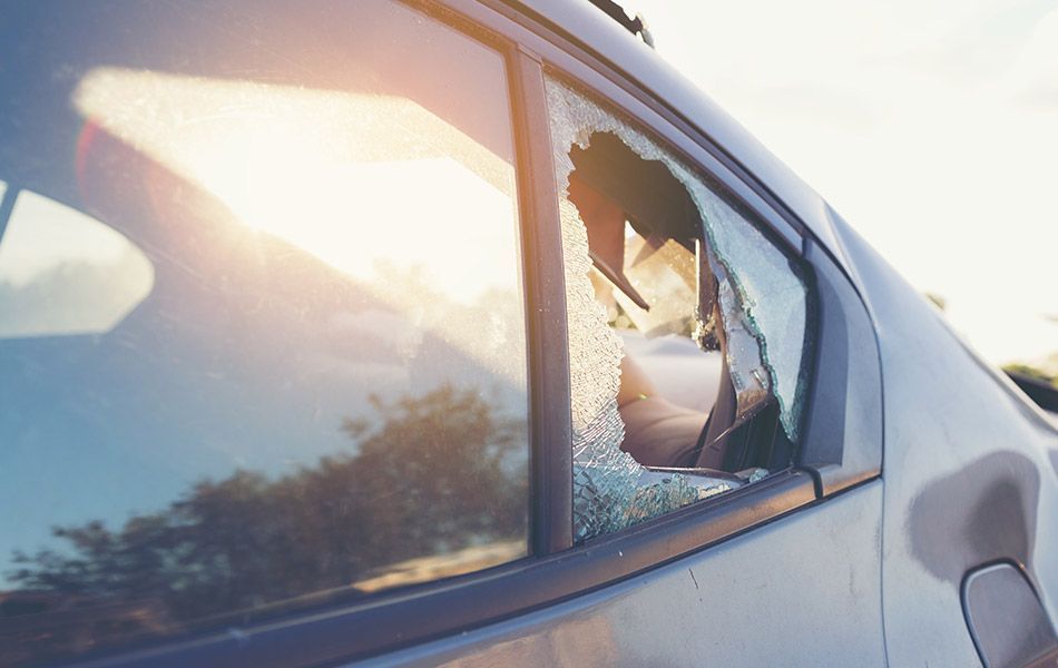 Damaged car side window with shattered glass and sunlight glare