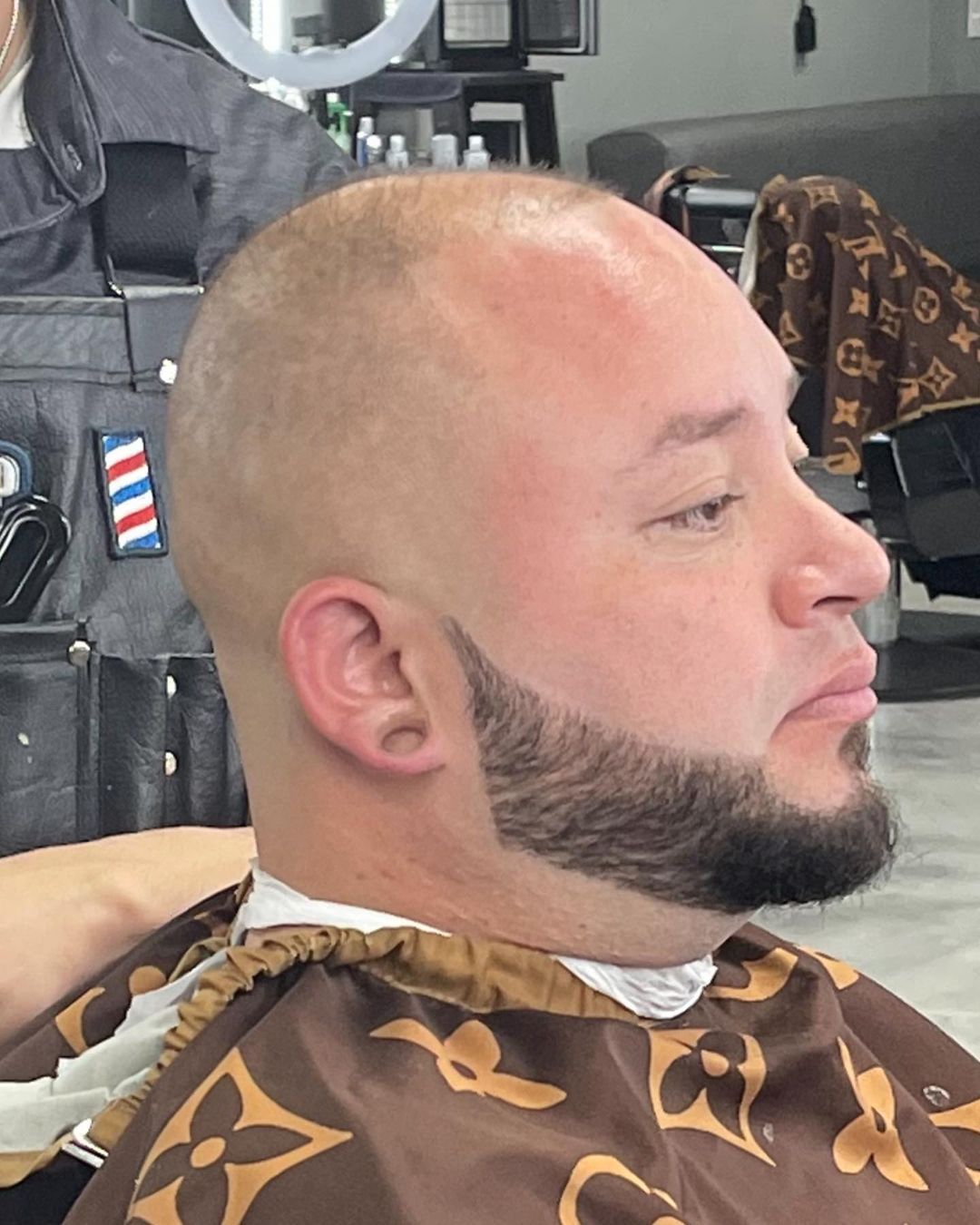 A man with a beard is getting his hair cut at a barber shop