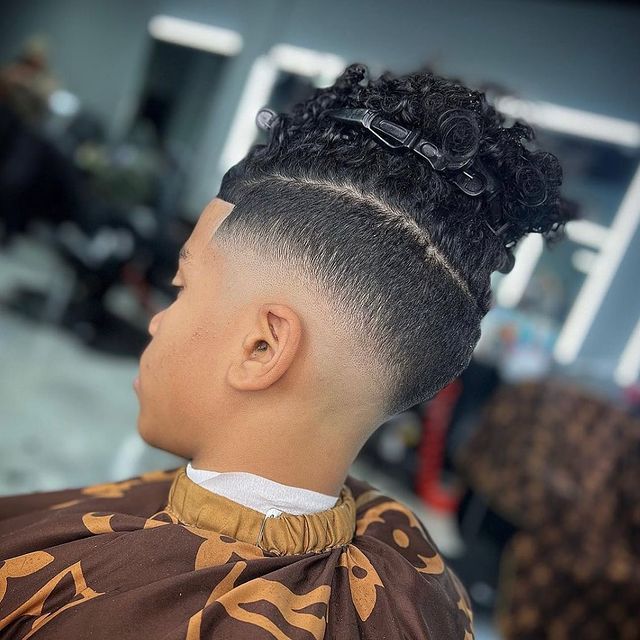 A young boy is getting his hair cut at a barber shop.