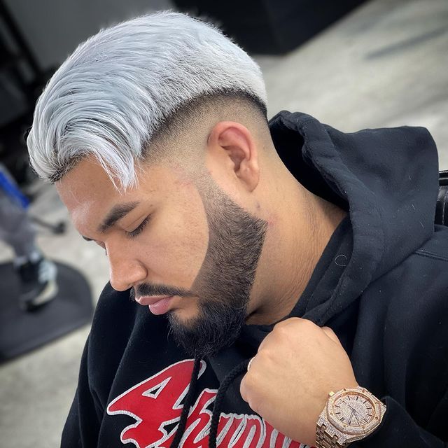 A man with a beard and white hair is wearing a watch