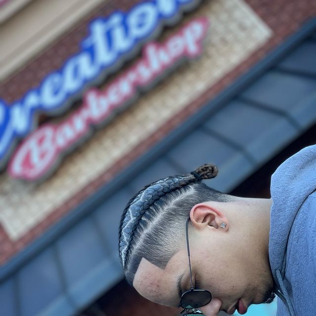 A man is standing in front of a barber shop